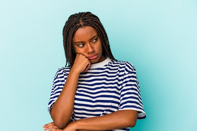 Jeune femme afro-américaine isolée sur fond bleu qui se sent triste et pensive, regardant l'espace de copie.