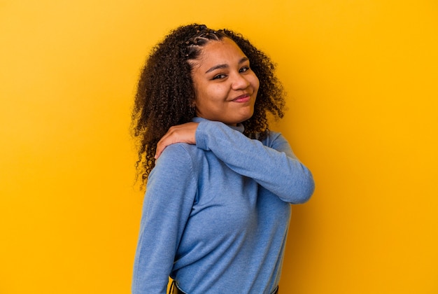 Jeune femme afro-américaine isolée sur fond jaune ayant une douleur à l'épaule.