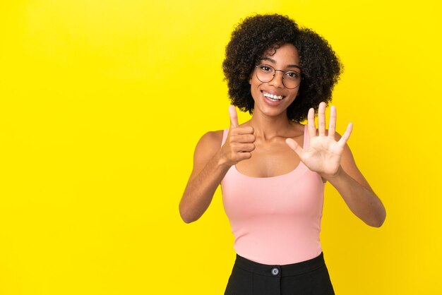 Jeune femme afro-américaine isolée sur fond jaune comptant six avec les doigts