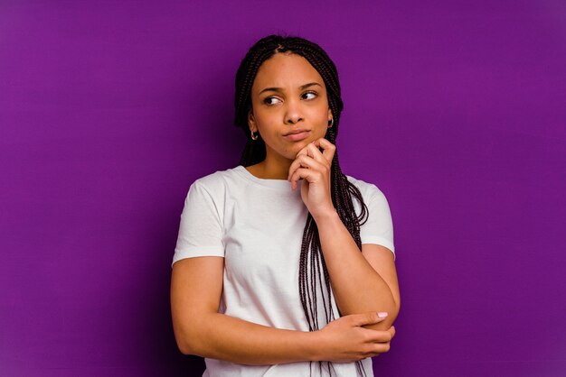 Jeune femme afro-américaine isolée sur fond jaune pensant et levant, réfléchissant, contemplant, ayant un fantasme.