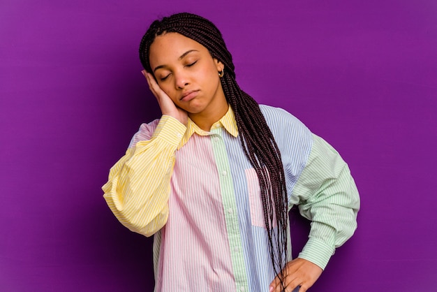 Jeune femme afro-américaine isolée sur fond jaune qui s'ennuie, fatiguée et a besoin d'une journée de détente.
