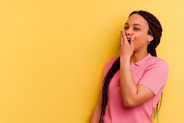 Jeune femme afro-américaine isolée sur fond jaune rire émotion heureuse, insouciante et naturelle.
