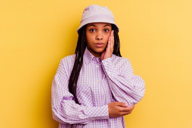 Jeune femme afro-américaine isolée sur fond jaune souffle sur les joues, a une expression fatiguée. Concept d'expression faciale.