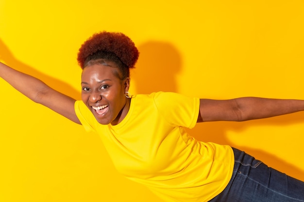 Jeune Femme Afro-américaine Isolée Sur Fond Jaune Souriant Et Dansant En Studio