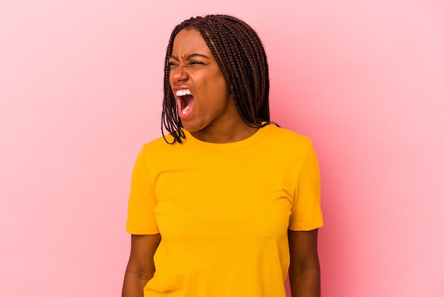 Jeune femme afro-américaine isolée sur fond rose criant très en colère, concept de rage, frustré.