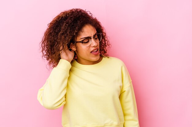 Jeune femme afro-américaine isolée sur fond rose essayant d'écouter un potin.