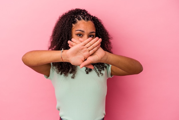 Jeune femme afro-américaine isolée sur fond rose faisant un geste de déni