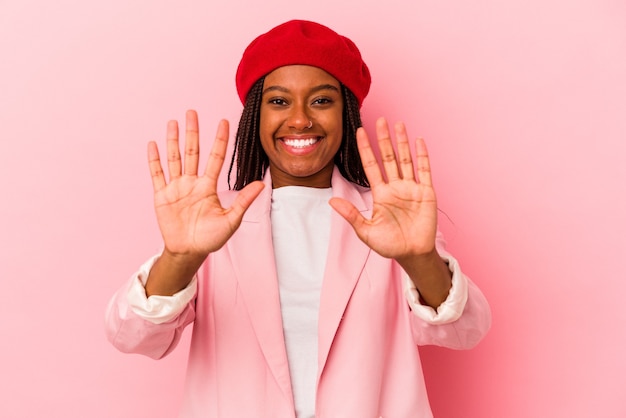 Jeune femme afro-américaine isolée sur fond rose montrant le numéro dix avec les mains.