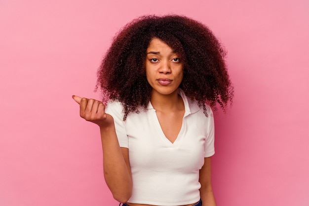 Jeune femme afro-américaine isolée sur fond rose montrant qu'elle n'a pas d'argent.