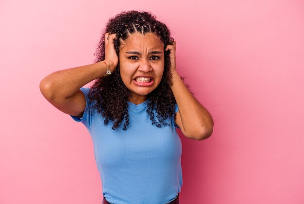 Jeune femme afro-américaine isolée sur fond rose pleurer, mécontente de quelque chose, l'agonie et le concept de confusion.