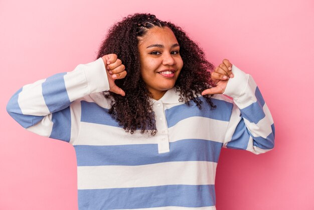 Jeune femme afro-américaine isolée sur fond rose se sent fière et confiante, exemple à suivre.