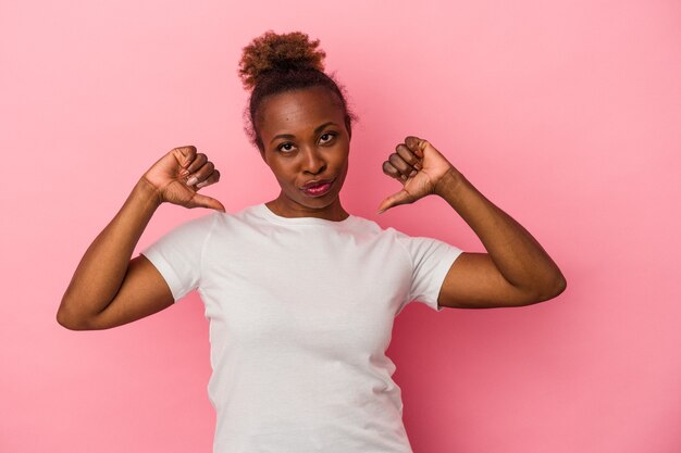 Jeune femme afro-américaine isolée sur fond rose se sent fière et confiante, exemple à suivre.