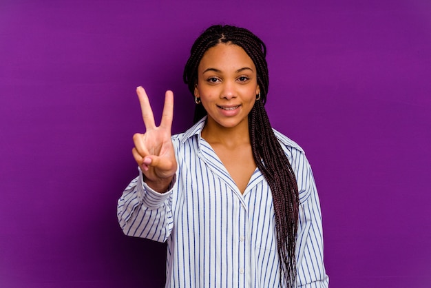 Jeune femme afro-américaine isolée sur jaune montrant le signe de la victoire et souriant largement.