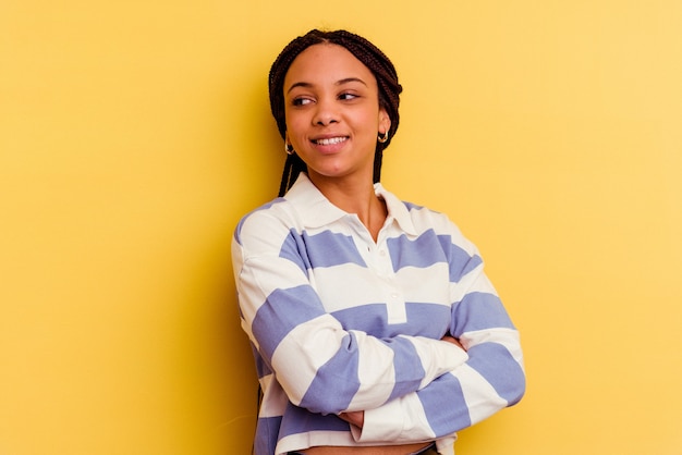 Jeune femme afro-américaine isolée sur jaune en riant et en s'amusant.