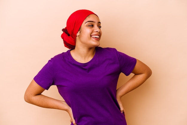 Jeune femme afro-américaine isolée sur un mur beige détendu et heureux en riant, cou tendu montrant les dents.