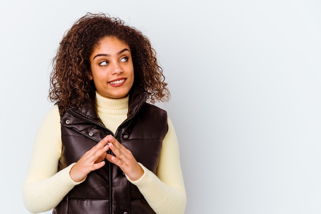 Jeune femme afro-américaine isolée sur un mur blanc constituant un plan à l'esprit, mettant en place une idée.