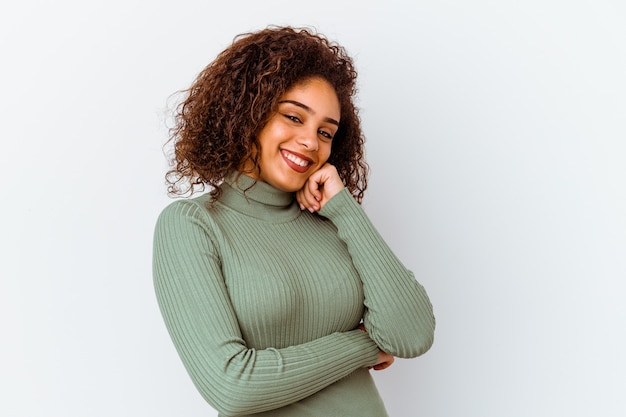 Jeune femme afro-américaine isolée sur un mur blanc souriant heureux et confiant, touchant le menton avec la main.