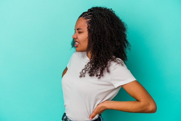 Jeune femme afro-américaine isolée sur un mur bleu souffrant d'un mal de dos