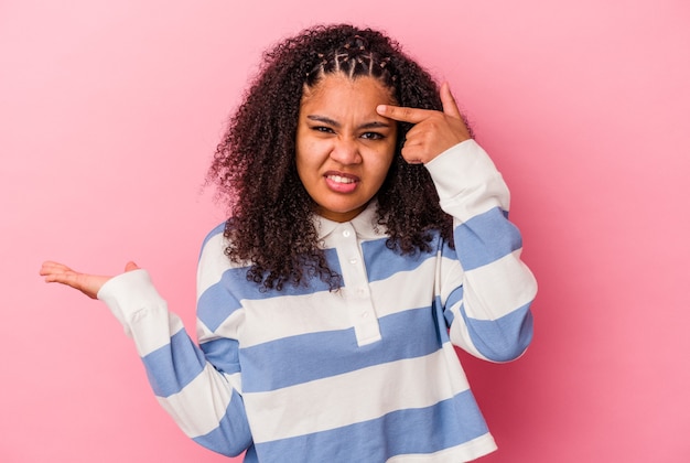 Photo jeune femme afro-américaine isolée sur un mur rose montrant un geste de déception avec l'index