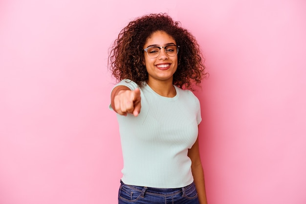 Jeune femme afro-américaine isolée sur un mur rose pointant vers l'avant avec les doigts.