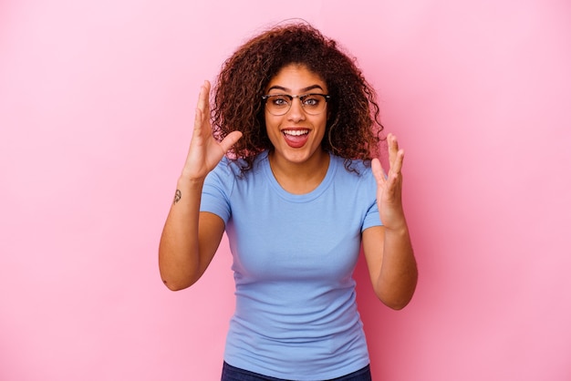 Photo jeune femme afro-américaine isolée sur un mur rose recevant une agréable surprise, excitée et levant les mains.