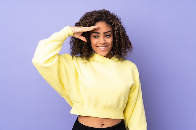 Jeune femme afro-américaine isolée sur le salut avec la main avec une expression heureuse