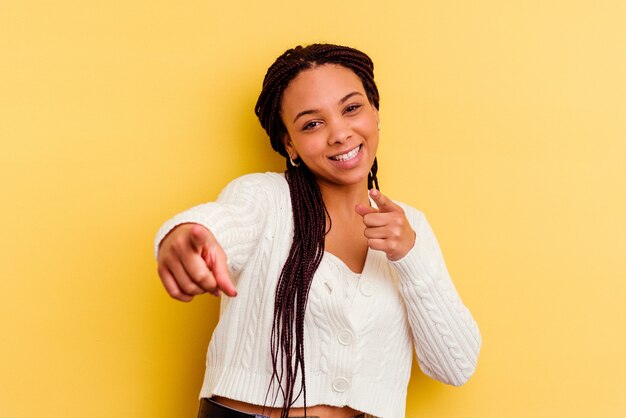 Photo jeune femme afro-américaine isolée sur des sourires joyeux jaunes pointant vers l'avant.