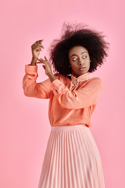 jeune femme afro-américaine en jupe de blouse de pêche et foulard de cou posant sur un fond rose pastel