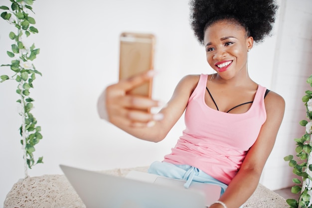 Jeune femme afro-américaine en maillot rose faisant selfie sur téléphone mobile