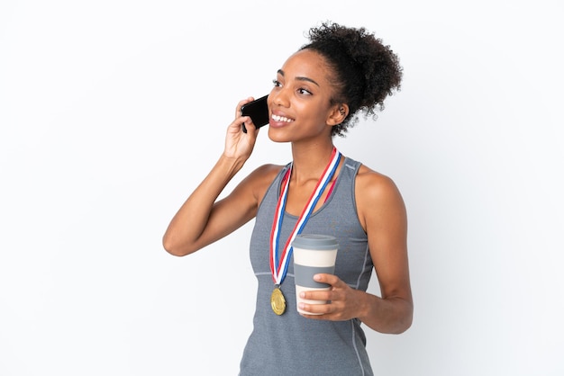 Jeune femme afro-américaine avec des médailles isolées sur fond blanc tenant du café à emporter et un mobile