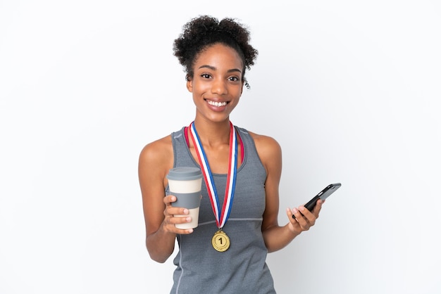 Jeune femme afro-américaine avec des médailles isolées sur fond blanc tenant du café à emporter et un mobile