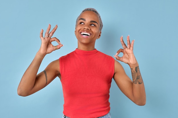 Une jeune femme afro-américaine montre un geste OK avec les deux mains se tient dans le studio