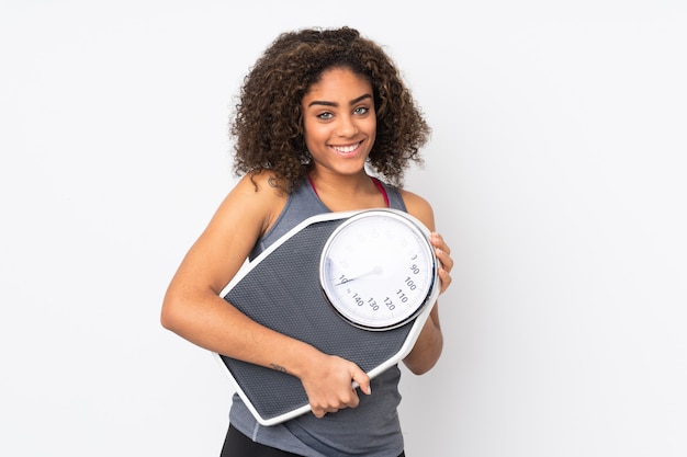 Jeune femme afro-américaine sur mur blanc avec machine de pesage