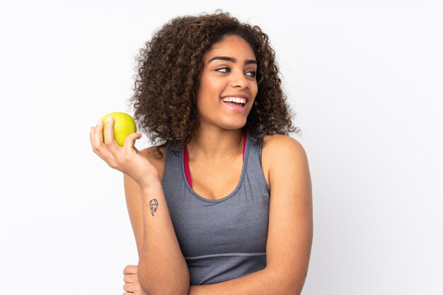 Jeune femme afro-américaine sur mur blanc avec une pomme et heureux