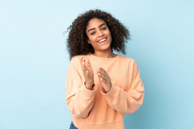 Jeune femme afro-américaine sur mur bleu applaudissant après présentation lors d'une conférence