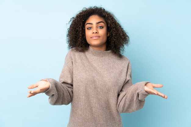 Jeune femme afro-américaine sur mur bleu ayant des doutes