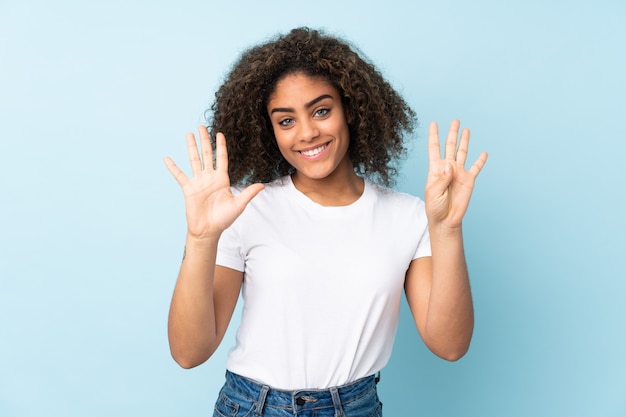 Jeune femme afro-américaine sur mur bleu comptant neuf avec les doigts