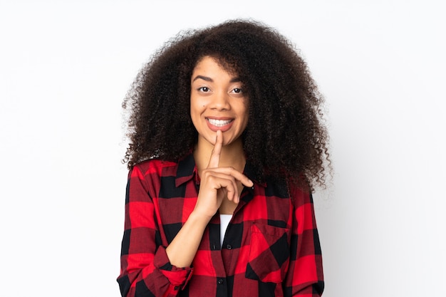 Jeune femme afro-américaine sur mur montrant un signe de silence mettant le doigt dans la bouche