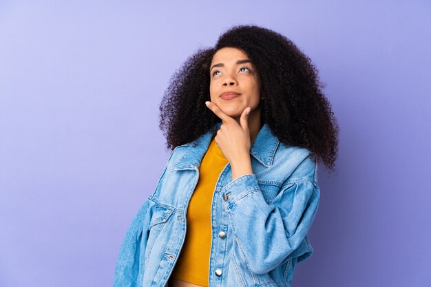 Jeune femme afro-américaine sur mur violet ayant des doutes