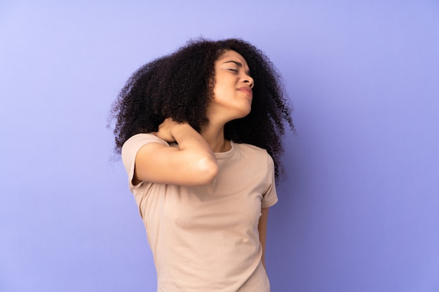 Jeune femme afro-américaine sur mur violet avec maux de tête