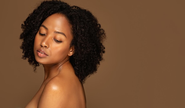 Jeune femme afro-américaine nue posant sur fond de studio marron