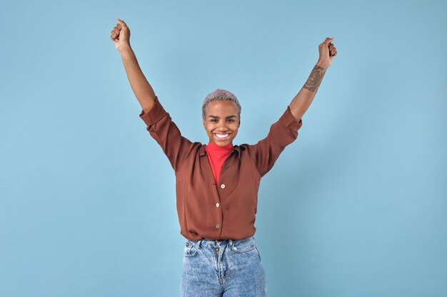 Une jeune femme afro-américaine optimiste lève la main en ressentant de l'euphorie.