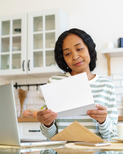 Jeune femme afro-américaine ouvrant et lisant le concept de lettre de réception de correspondance par courrier