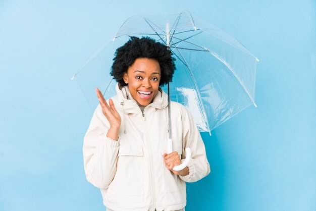 Jeune femme afro-américaine avec un parapluie isolé surpris et choqué.