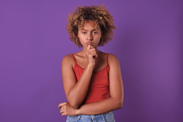 Une jeune femme afro-américaine pensive et concentrée se gratte le menton en studio