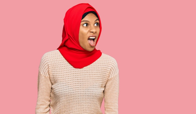 Jeune femme afro-américaine portant un foulard hijab islamique traditionnel en colère et folle criant frustré et furieux, criant de colère. rage et concept agressif.