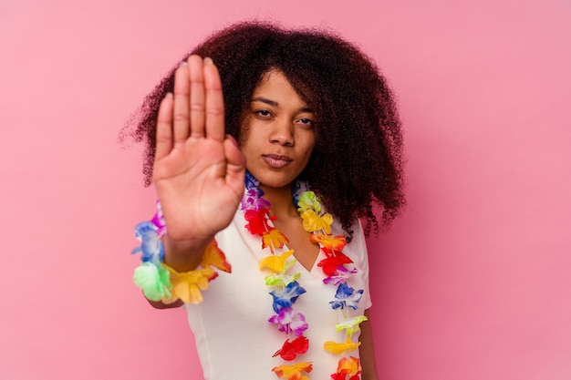 Jeune femme afro-américaine portant un truc hawaïen debout avec la main tendue montrant le panneau d'arrêt, vous empêchant.