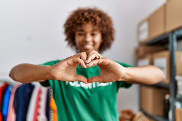 Photo jeune femme afro-américaine portant l'uniforme des bénévoles faisant le symbole du coeur avec les mains au centre de charité
