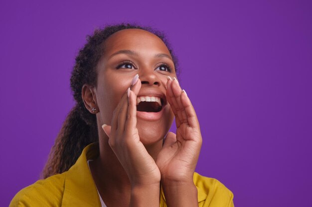 Jeune femme afro-américaine positive met les mains à la bouche pour crier à haute voix