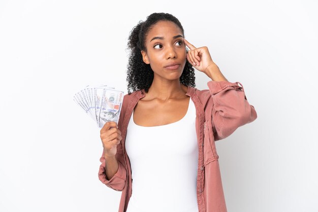 Jeune femme afro-américaine prenant beaucoup d'argent isolé sur fond blanc ayant des doutes et pensant